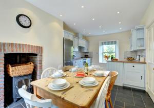 a kitchen with a wooden table with chairs and a fireplace at St Teresas Cottage in Saint Mawgan