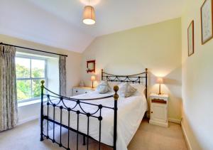 a bedroom with a black bed and a window at St Teresas Cottage in Saint Mawgan