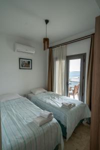 two beds in a bedroom with a view of the ocean at Ilya Apart 1 in Bodrum City