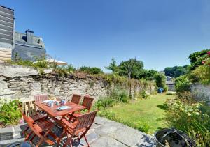 a patio with a table and chairs and a stone wall at 6 St Saviours Lane in Padstow