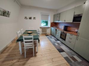 uma cozinha com mesa e cadeiras e uma cozinha com armários brancos em Ferienwohnung Gasthof Port em Naunheim