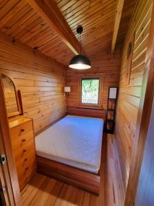 um pequeno quarto com uma cama num chalé de madeira em Leśna ostoja Poddąbie em Poddabie