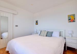 a white bedroom with a large white bed at The Lookout - Sennen in Sennen