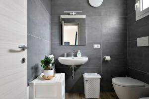 een badkamer met een wastafel, een toilet en een spiegel bij KT House - Tortolì in Tortolì