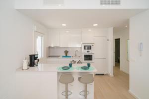 una cucina bianca con bancone e due sgabelli di Bonita a Avileses