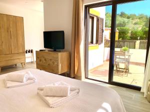 a bedroom with a bed and a tv and a balcony at Quinta das Andorinhas in Carvoeiro
