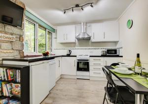 een keuken met witte kasten en een tafel met stoelen bij Breakaway Lodge in Carbis Bay