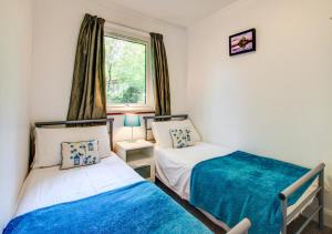 twee bedden in een kleine kamer met een raam bij Breakaway Lodge in Carbis Bay