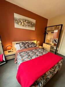 a bedroom with a large bed with a red blanket at Hôtel de Guise SARL in Guise