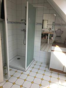 a bathroom with a shower and a tiled floor at Maison près de Bon repos in Laniscat