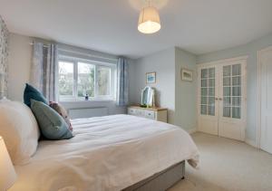 a bedroom with a large white bed with a window at St Mellyn in Mevagissey