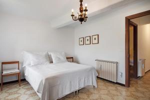 a white bedroom with a white bed and a chandelier at Casa Luci in Levanto
