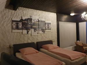 ラーティンゲンにあるアム ハーレンバート ホテル ガルニのベッド2台付きの部屋、壁に2枚の写真が飾られています。