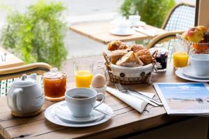 a table with a cup of coffee and a basket of food at Hôtel de Lion sur Mer in Lion-sur-Mer