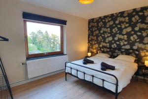 ein Schlafzimmer mit einem Bett mit einem großen Fenster in der Unterkunft D'Hestia - Gîte avec vue imprenable sur Huy in Huy