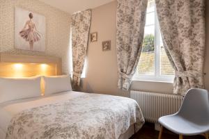 a bedroom with a bed and a window and a chair at Hôtel de Lion sur Mer in Lion-sur-Mer