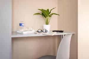 a white table with a plant and glasses on it at Hôtel de Lion sur Mer in Lion-sur-Mer
