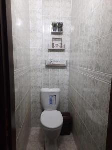 a bathroom with a toilet and a tiled wall at Квартира возле оперного театра 22 in Almaty