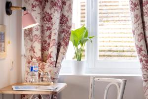 a table with a lamp and a window at Hôtel de Lion sur Mer in Lion-sur-Mer