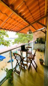 een patio met een tafel en stoelen en een laptop bij Casa com os pés no mar em Iriri ES in Anchieta