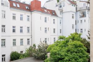 eine Reihe weißer Gebäude mit Bäumen im Vordergrund in der Unterkunft Charming Apartment near Center in Wien
