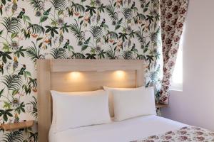 a bedroom with a bed with a floral wallpaper at Hôtel de Lion sur Mer in Lion-sur-Mer