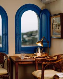 Hostal de la Plaça - Hotel Boutique في كابرايلس: غرفة زرقاء مع طاولة ونوافذ اثنين