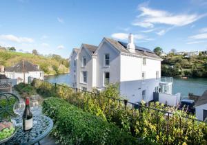 a white house with a table with a bottle of wine at Waters Reach in Fowey