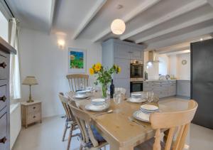 a dining room with a table and chairs and a kitchen at The Smithy in Gunwalloe