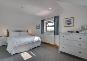 a bedroom with a bed and a dresser and a window at The Smithy in Gunwalloe