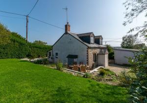 a small house in a yard with a green lawn at The Smithy in Gunwalloe