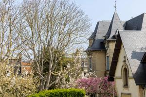 a group of buildings with trees and a church at Hôtel de Lion sur Mer in Lion-sur-Mer