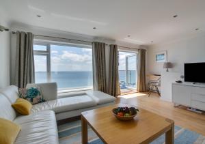 a living room with a white couch and a large window at Neptune House in Porthleven