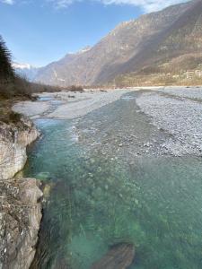 Un río con agua verde y rocas junto a una montaña en Maggia by the River, en Giumaglio