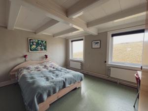 um quarto com uma cama e duas janelas em Akraberg Lighthouse Lodge em Sumba