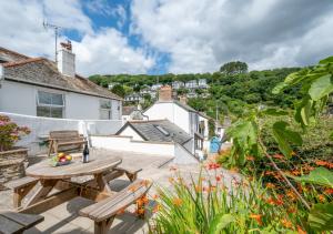 a patio with a table and benches on the roof of a house at Auntie Katies Cottage in Looe