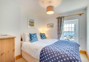 a bedroom with a blue and white bed and a window at Bay Cottage in Gorran Haven