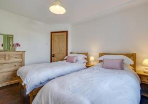 two beds in a bedroom with two tables and two lamps at Auntie Katies Cottage in Looe
