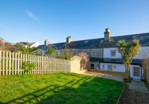 a fence in front of a house with a yard at Bay Cottage in Gorran Haven