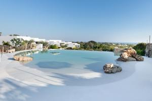 una piscina con acqua blu e rocce di Masseria Samenti a Torre Suda