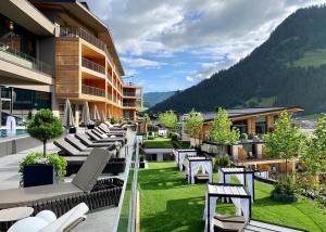 uma varanda do hotel com espreguiçadeiras e um relvado em DAS EDELWEISS - Salzburg Mountain Resort em Grossarl