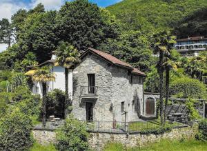 una antigua casa de piedra con palmeras en una colina en Palm Cottage en Locarno