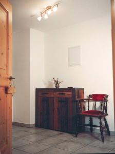 a room with a chair and a wooden cabinet at Apartment im Obstgarten in Rottau