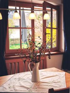 a vase with flowers on a table with a window at Apartment im Obstgarten in Rottau