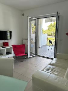 un soggiorno con divano e sedia rossa di Suite Pineto Mare Mykonos Residence a Pineto