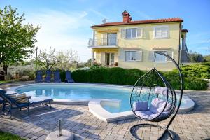 a swimming pool with a swing and a house at Apartment Laetitia in Kaštelir