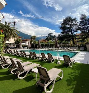 a row of chaise lounge chairs next to a swimming pool at Palace Hotel Città in Arco