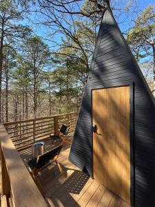a black triangular house with a door on a deck at Loblolly Pines Adventure Aframe #1 in Eureka Springs