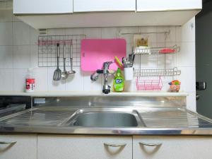 a kitchen sink with a pink cutting board and utensils at Ewha Hostel in Seoul