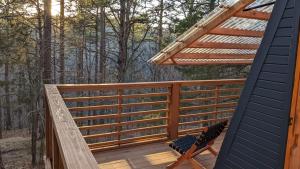 a deck with a pergola and a chair at Loblolly Pines Adventure Aframe #1 in Eureka Springs